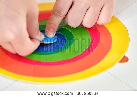 Close Up. Child's Hand, Kid's Hand Is Putting Last Piece Jigsaw Of Color Puzzle On The Target. Targe