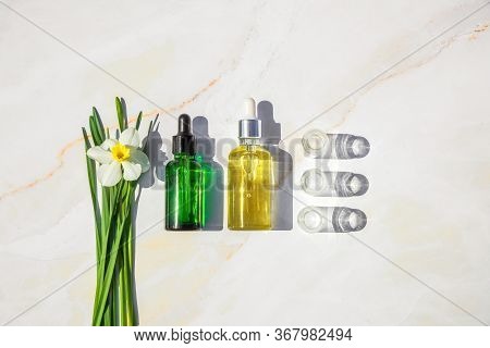 Homeopathic Oil, Serum And Bottles With Plants Onon Marble Background. Concept Of Natural Organic Co