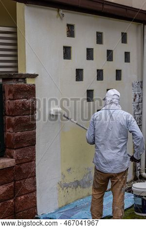 Painter Worker Adding Undercoat Foundation Paint Onto Wall With Roller At Residential Building In Re