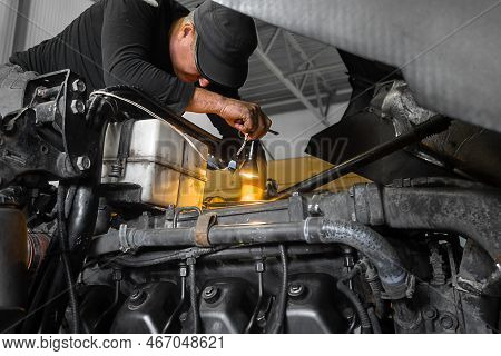 Car Mechanic Repairs Large Truck Or Tractor In Workshop. Professional Mechanic Repairs Truck Engine.