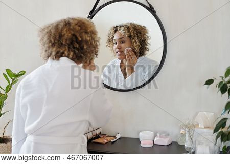 Young Pretty Woman In White Bathrobe Applying Refreshening Toner On Face