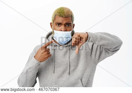 Covid 19, Coronavirus Concept. Black Man Shows Wrong Way Of Wearing Medical Face Mask, Makes Thumbs 
