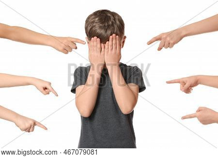 Boy Covering Face With Hands And Kids Pointing At Him On White Background. Children's Bullying