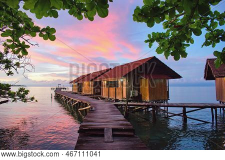 Beautiful Sunset Above Typical Water Bungalows On The Beach - Waigeo Island, Raja Ampat, West Papua,