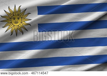 Uruguay Flag With Big Folds Waving Close Up Under The Studio Light Indoors. The Official Symbols And