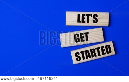 Three Wooden Blocks With The Text Lets Get Started On A Bright Blue Background. Copy Space