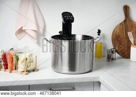 Pot With Sous Vide Cooker And Vacuum Packed Food Products In Kitchen. Thermal Immersion Circulator