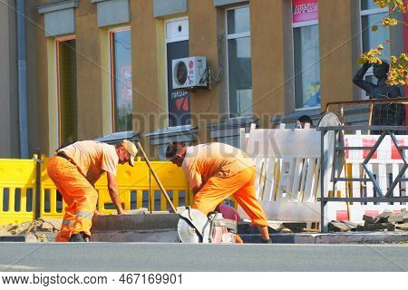 Samara, Russia - Circa March, 2022: Uniformed Road Workers Work On A City Street Laying A Curb