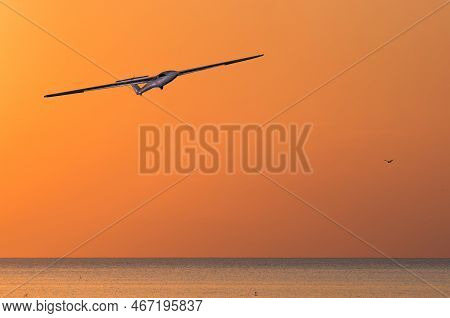 The Glider Flies At Sunset Over The Sea. Photocollage. Selective Focus.