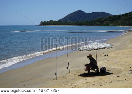 One Unrecognizable Man Sitting At The Beach Fishing