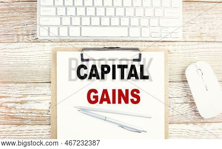 Capital Gains Text On Clipboard With Keyboard On Wooden Background