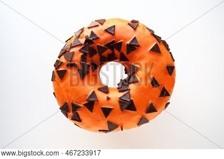 Halloween Donut With Orange Frosting And Chocolate Triangles As A Sweet Decorative Topping. Children