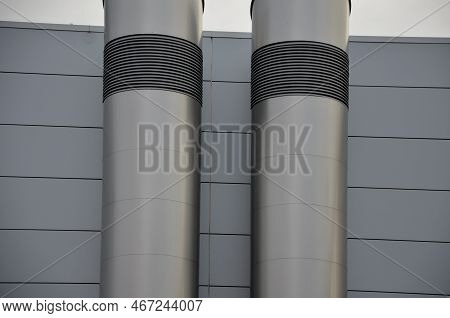 Industrial Gray Building With Sheet Metal Facade Of Repeating Rectangle Paneling. On Wall Are Two Si