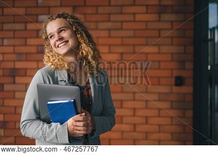 Portrait Of Teenager Girl Posing Holding Book And Laptop, Smiling Looking Away Standing Against Mode
