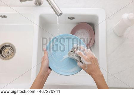 Woman Washing Plate Above Sink In Modern Kitchen, Top View