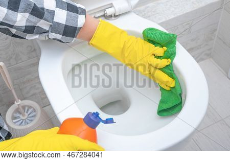 Close Up Hand With Detergent Cleaning Toilet. Cleaning Service. Close Up Hands Wearing Yellow Protec