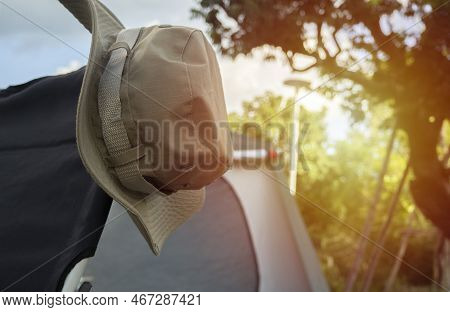 Clopped Picture Of Hiking Hat Hanging On A Camping Chair With The Background Is A Blurred Image Of T