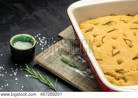 Homemade Italian Focaccia Modenese, With Rosemary And Olive Oil On A Wooden Board. Food Recipe Backg