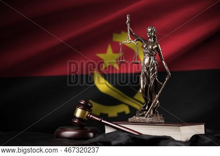 Angola Flag With Statue Of Lady Justice, Constitution And Judge Hammer On Black Drapery. Concept Of 