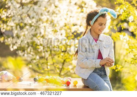 Teenage Girl Paints Easter Eggs In The Garden.