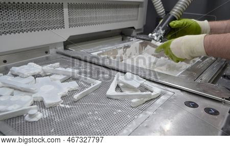 Male Worker Taking Out Models From White Polyamide Powder In Working Chamber Of 3d Printer, Cleaning