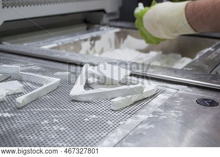 Male Worker Taking Out Models From White Polyamide Powder In Working Chamber Of 3d Printer, Cleaning