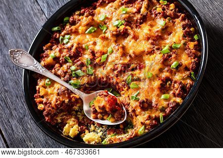 Cajun Beef Cornbread Casserole Topped With Melted Red Cheddar Cheese And Scalions In Baking Dish On 