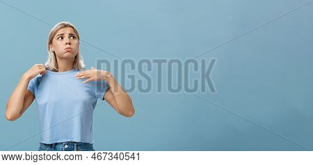 Girl Feeling Discomfort From Heat Standing Over Blue Background In Fug Breathing Out And Frowning Lo