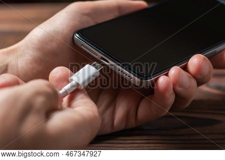 Charging A Smartphone Via A Usb Cable And A Power Supply. A Black Smartphone Hanging With A Usb Char