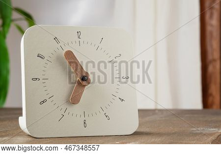 Beige Clock On A Wooden Table Showing Time 18 Hours 55 Minutes With Copy Space. Analog Clock With: 1