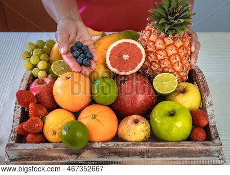 Close-up On A Wooden Basket Full Of Colorful Fresh Fruit. Female Hands Holding Some Blueberries. Hea