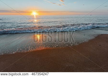Sunrise On The Seashore On The Italian Riviera. Sandy Beach And Waves Reflecting The Sunlight In The