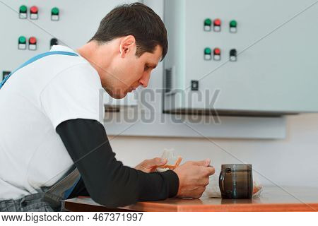 Lunch Break. Eating In Workplace During Work. Caucasian Man In Work Suit Sits At Table In Production