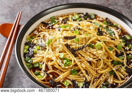 Korean Soup With Soba Noodles, Seaweed, Green Onions And Sesame Seeds Close-up In A Bowl On The Tabl