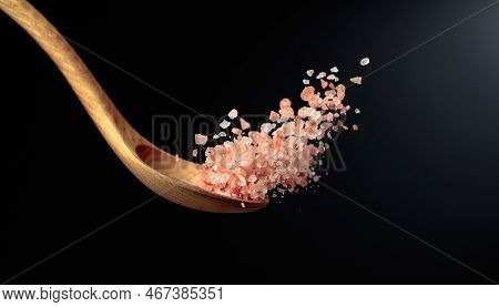 Pink Himalayan Salt Is Poured With A Wooden Spoon. Himalaya Salt On A Dark Background. Copy Space.