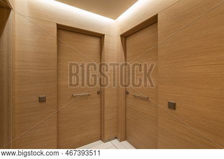 Soft Light From Niche Under Ceiling Illuminates Doors And Walls In Common Corridor. Interior Is Made