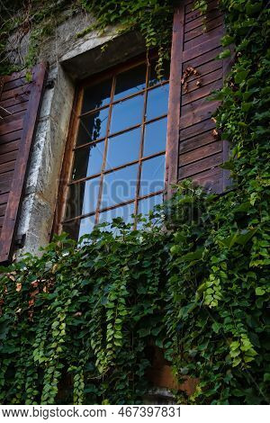 Talloires, France - September 08 2020 : Ivy Has Over Grown And Old Historic French House With A Wind