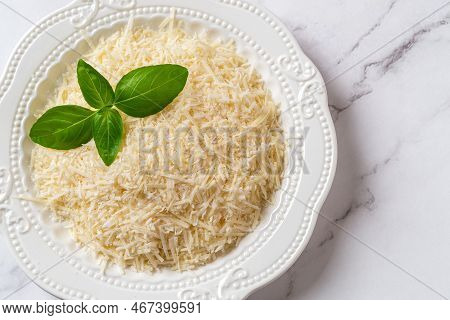 Shredded Parmesan On A Plate Closeup. Plate Of Grated Grana Padano Cheese Over Marble Background. It