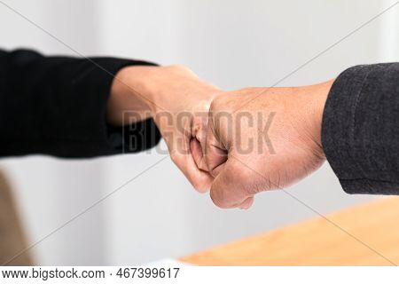 Close Up Of Young Businessman And Businesswoman Making A Fist Bump; Business People Wear Suit With F