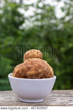 Closeup Of  Organic Palm Jaggery Or Gur In A White Bowl Isolated On Wooden Table In Vertical Orienta