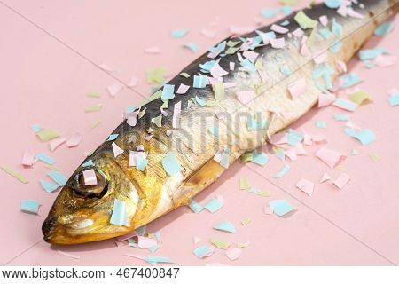 Fish Covered Microplastic On A Pink Plate. Impact Of Micro Plastic On The Food Chain. The Idea Of Mi