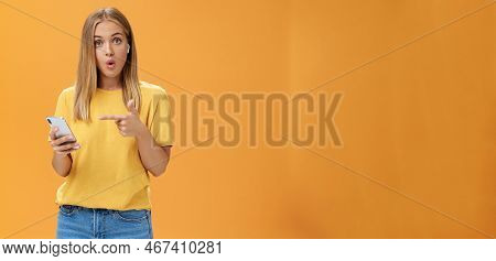 Wman Impressed By Wireless Earphones Connecting To Smartphone Themselves Pointing At Device Screen Q