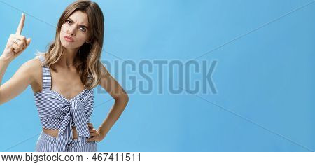 Strict Serious-looking Young Mother Giving Directions Raising Index Finger And Frowning To Look Scar