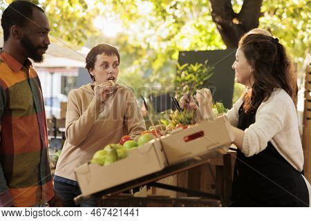 Multiracial Couple Tasting Bio Organic Produce At Farmers Market, Selling Locally Grown Fruits And V