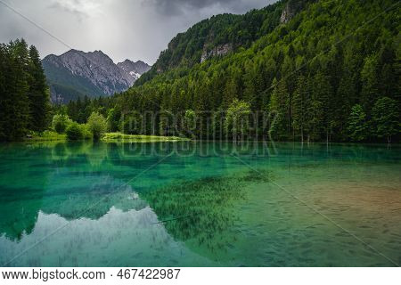 Alpine Spring Landscape With Stunning Mountain Lake. Plansarsko Lake With Green Forest In Jezersko V