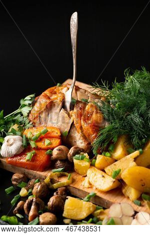 Fried Chicken With Potatoes And Mushrooms On A Dark Background. Smoked Poultry With Vegetables And A