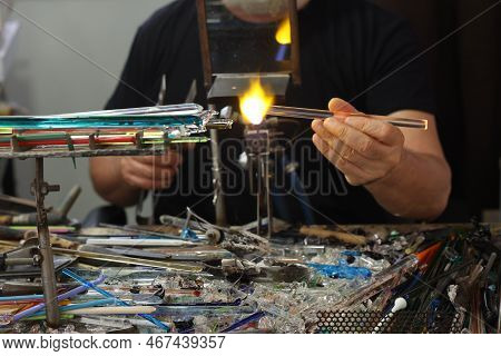 Glassworker While Shaping The Glass With A Very High Temperature Flame In Its Artisan Workshop In Ve