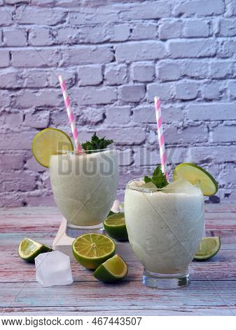 Brazilian Lemonade In Two Glasses Decorated With Lime Slices And Mint. Refreshing Creamy Drink. Vert