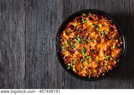 Cajun Beef Cornbread Casserole Topped With Melted Red Cheddar Cheese And Scalions In Baking Dish On 