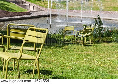 Movable Chairs In The Public Space Of A Modern City. Free Green Steel Chairs In The Park On The Lawn